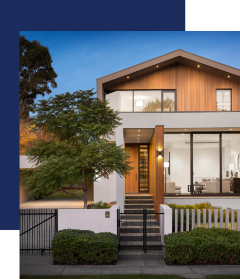 modern two-story home with wood and white exterior, a peaked roof, and a front gate at twilight